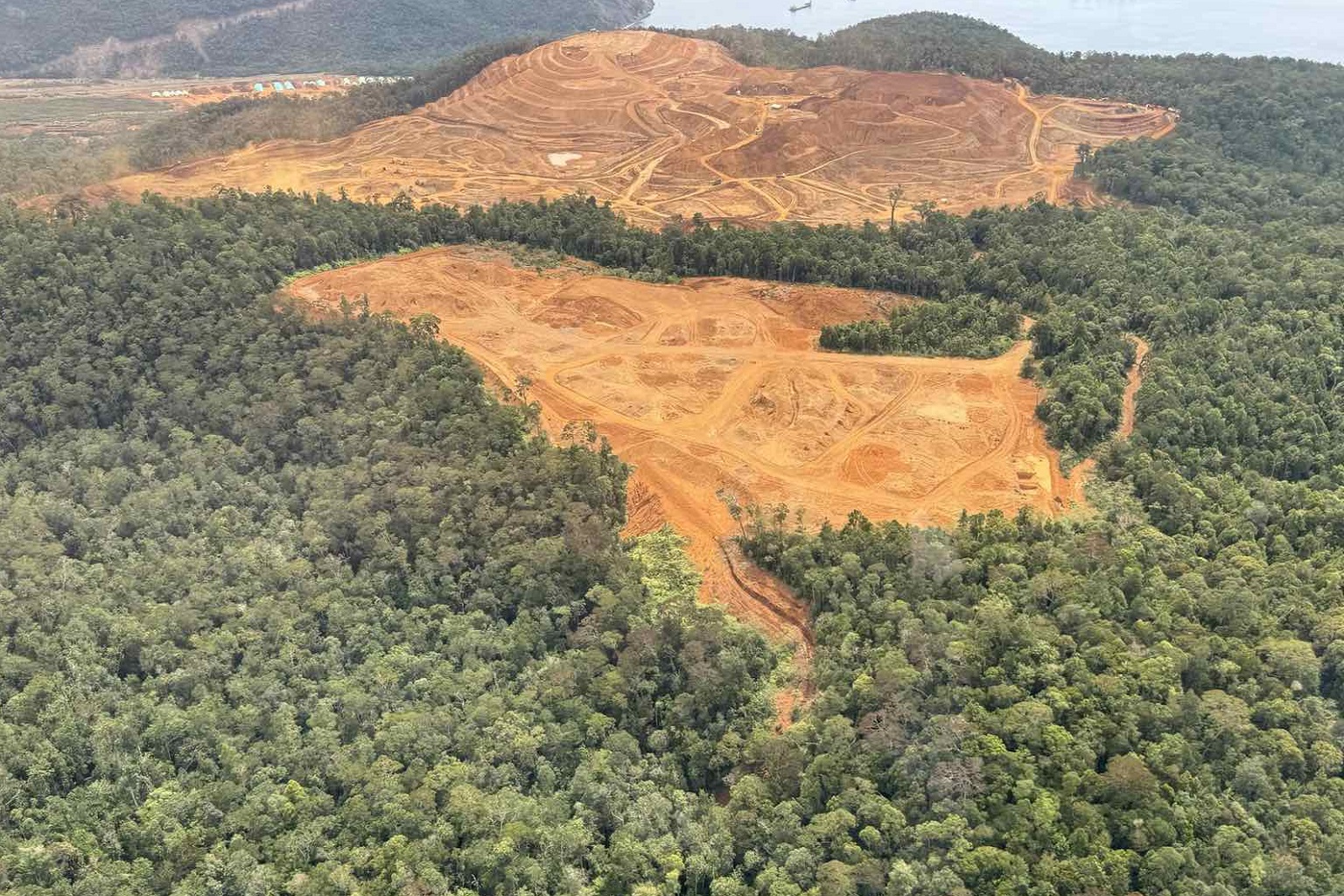 Aerial view of a stripped orange nickel pit surrounded by intact forest in Davao Oriental